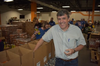 shippers group executive team member hugh tait smiles and packs commodity boxes at north texas food bank