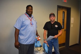 Two TSG drivers pose for a photo while holding their snacks and swag