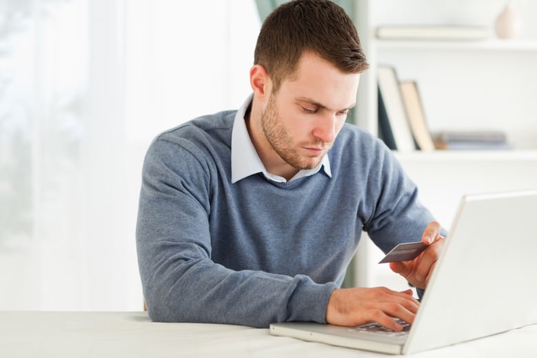 Young male entering credit card information in his laptop